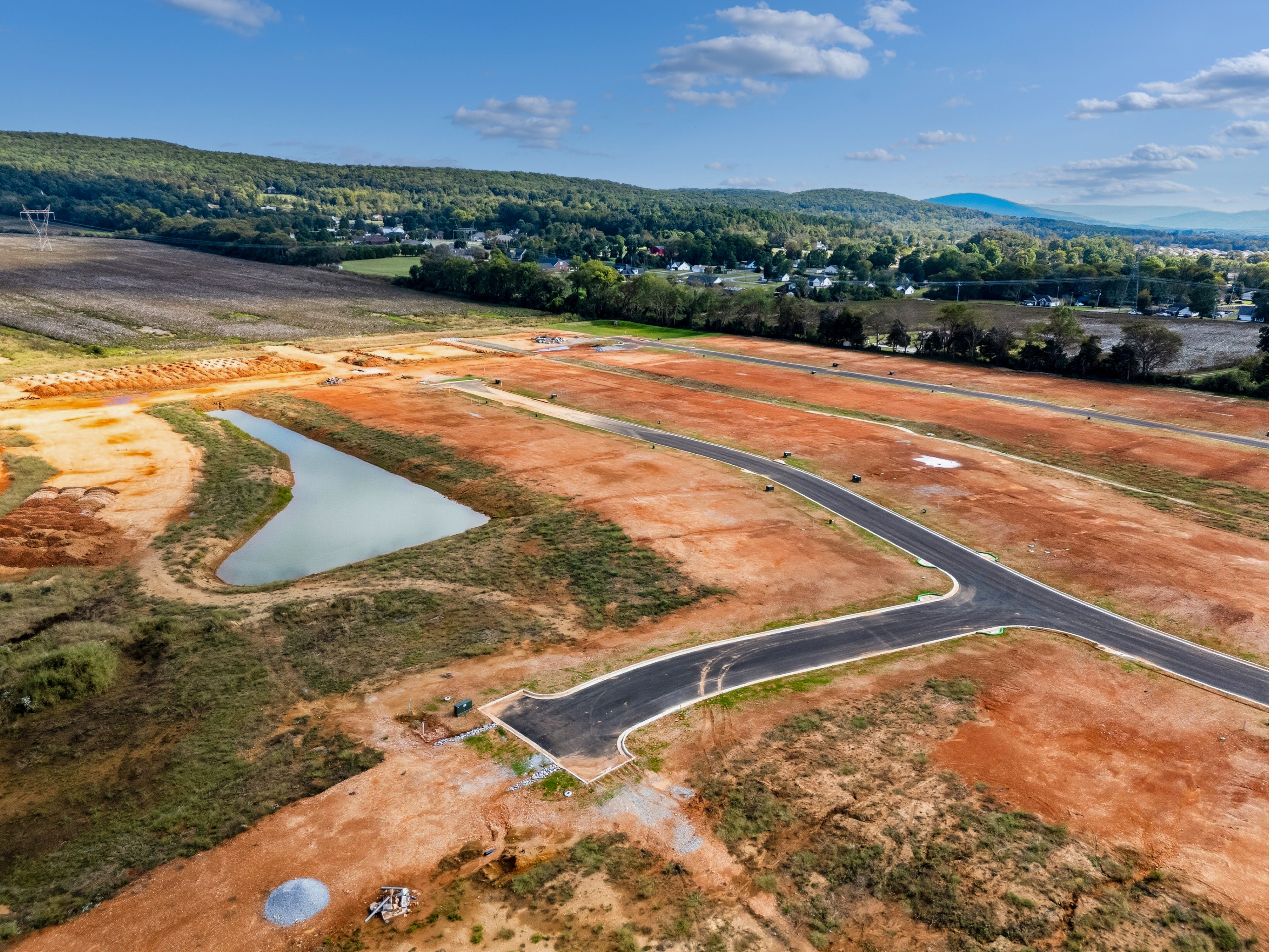 Aerial view of Berry Cove development in New Market Alabama with red dirt roads pond and surrounding hills by Davidson Homes