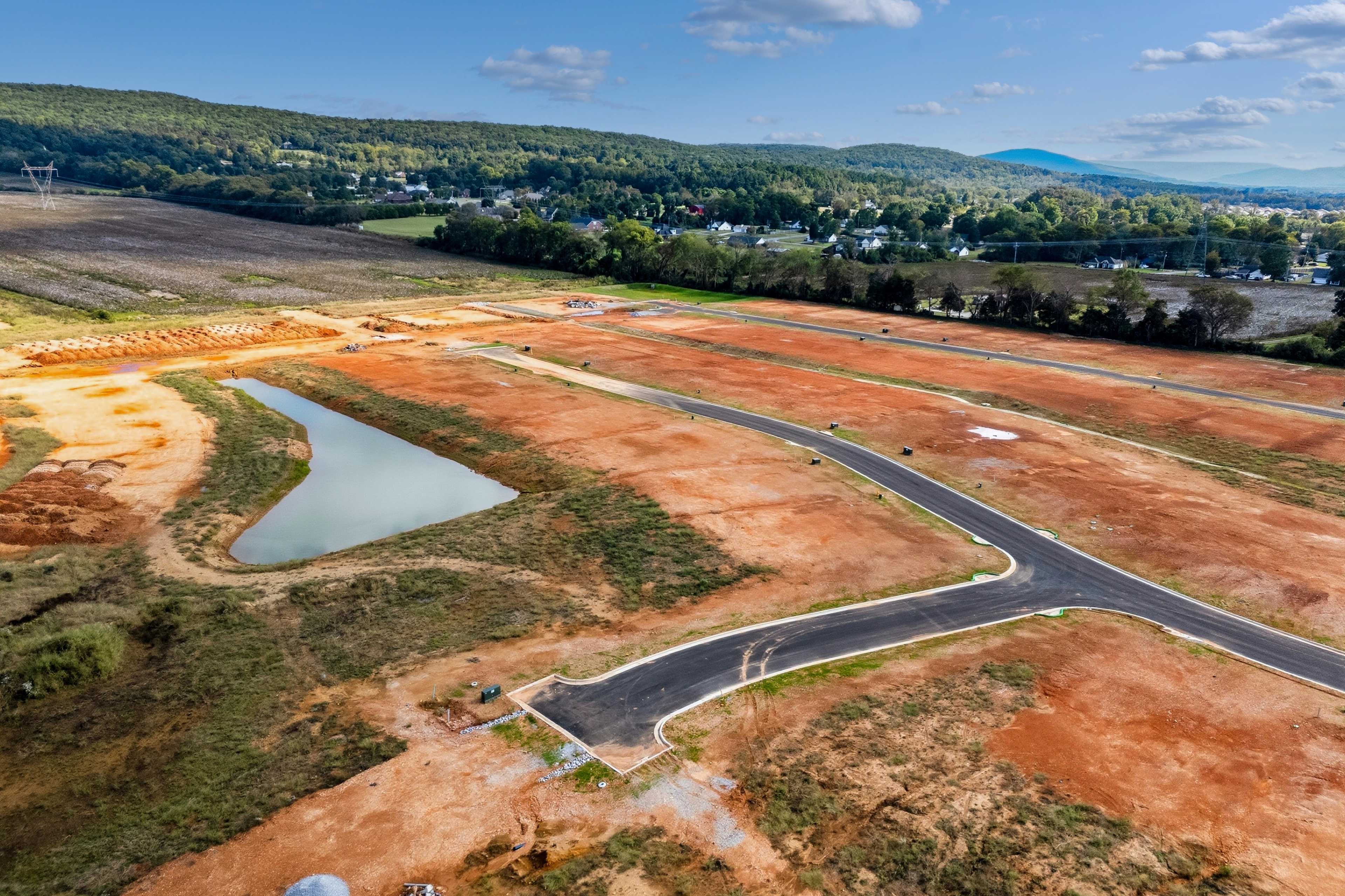 Aerial view of Berry Cove development in New Market Alabama with red dirt roads pond and surrounding hills by Davidson Homes