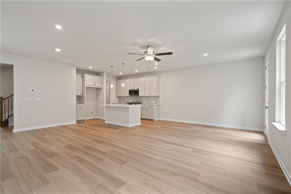Modern white kitchen with island, stainless appliances, hardwood floors in The Marion B by Davidson Homes, Kennesaw, GA