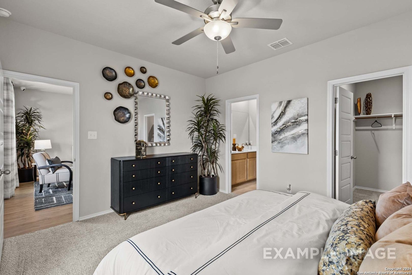 Elegant master bedroom suite with white bed, black dresser, walk-in closet, and en-suite bath in Davidson Homes The Sabine B, San Antonio