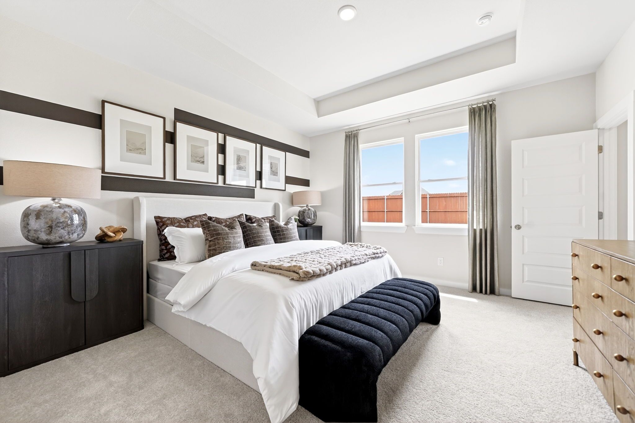 Modern primary bedroom at Mesa Vista in San Antonio by Davidson Homes with tray ceiling and neutral decor.