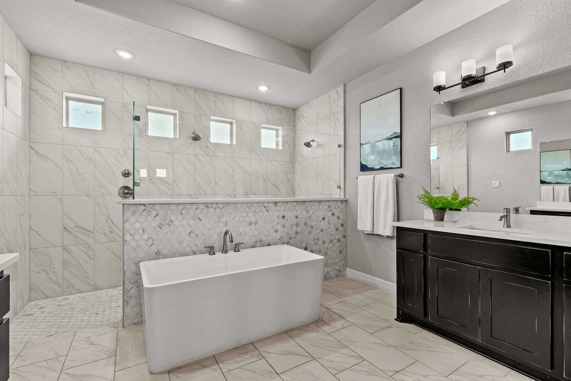 Luxurious master bathroom in The Summerlin B featuring freestanding tub, glass shower, marble tiles, double vanity