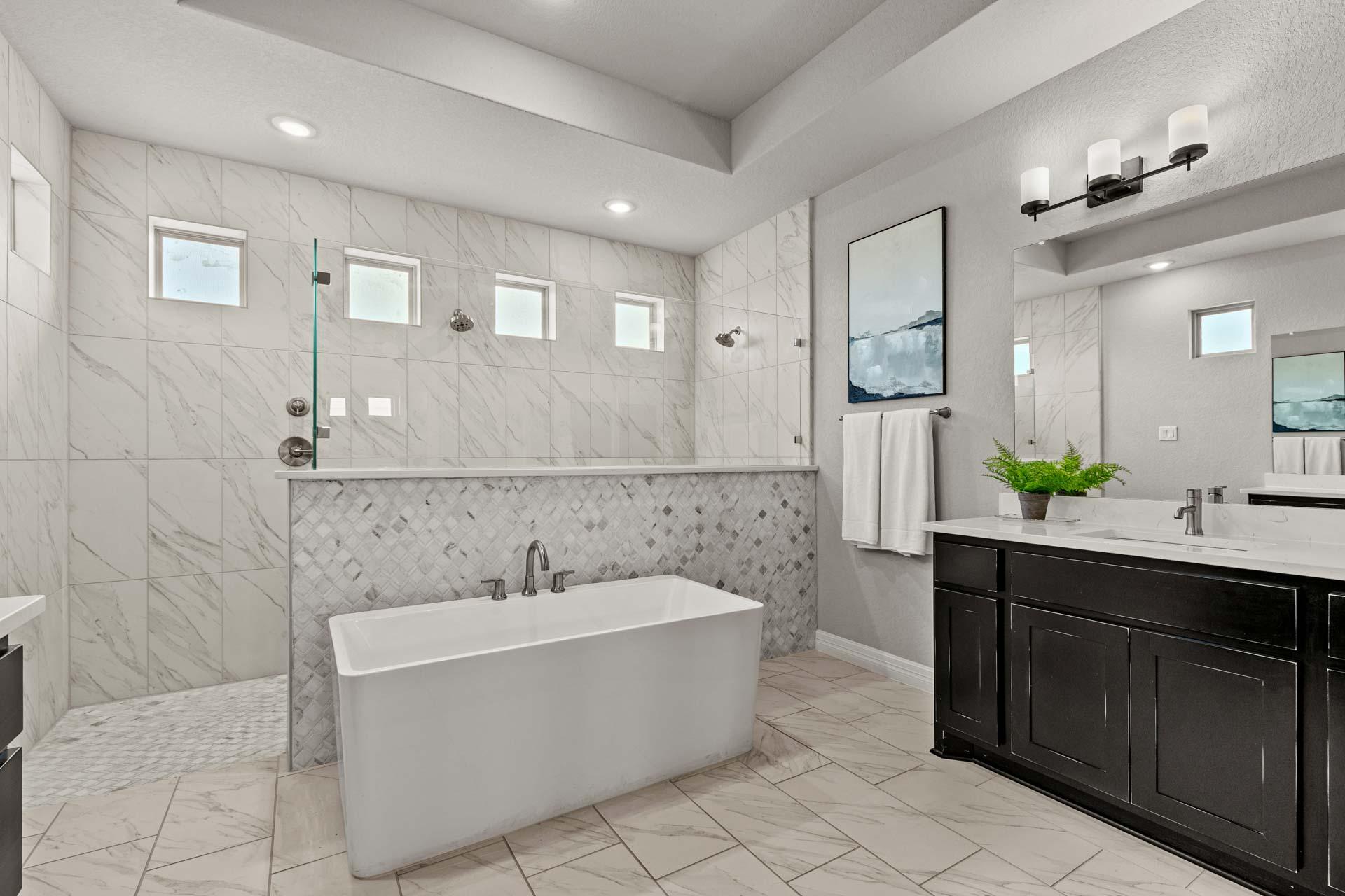 Spacious primary bathroom at Potranco Oaks in Castroville TX with freestanding tub, walk-in shower, and double vanity by Davidson Homes