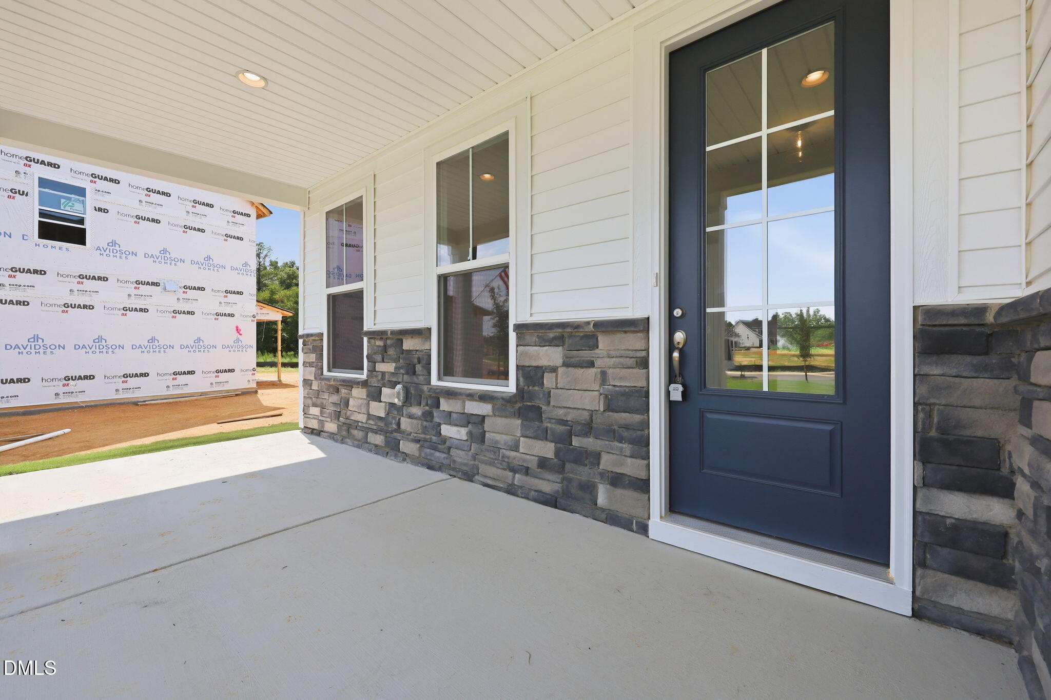 Covered front porch with stone accents and blue door on The Magnolia B floor plan in Retreat at North Main, Lillington, NC.