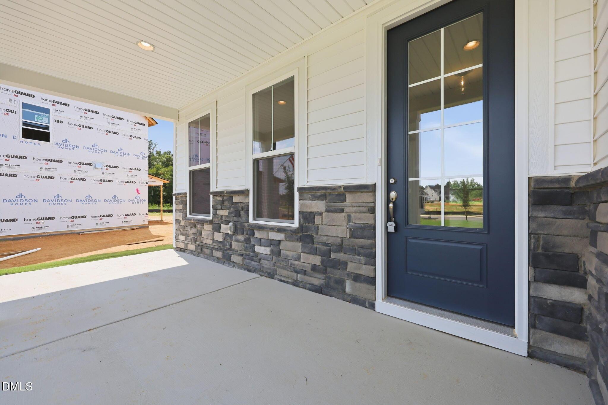 Covered front porch with stone accents and blue door on The Magnolia B floor plan in Retreat at North Main, Lillington, NC.