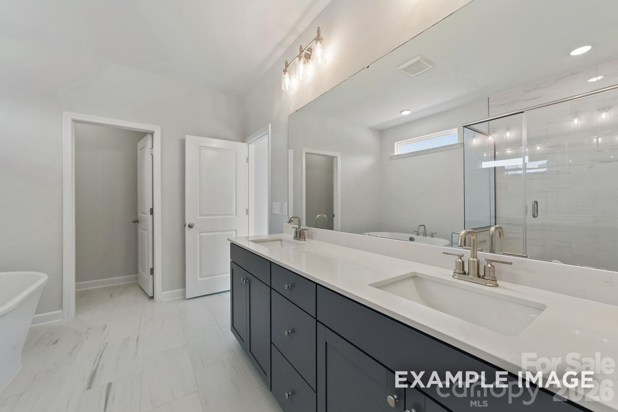 Modern primary bathroom with dual-sink vanity, soaking tub, and glass shower in Davidson Homes Magnolia B, Mooresville, NC.