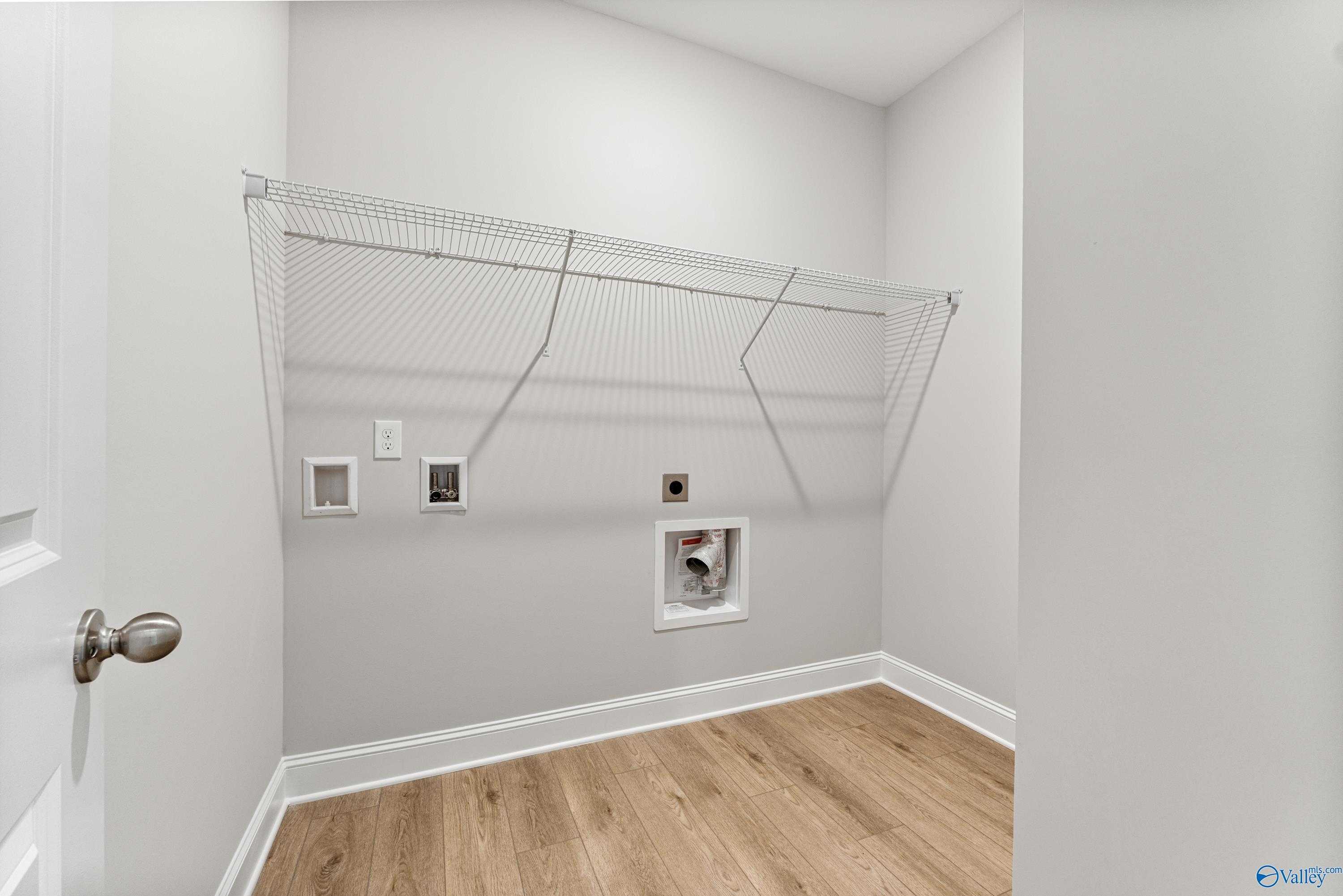 Functional laundry room with wire shelving, dryer vent, outlets, and oak floors in Davidson Homes The Daphne C, Athens, AL