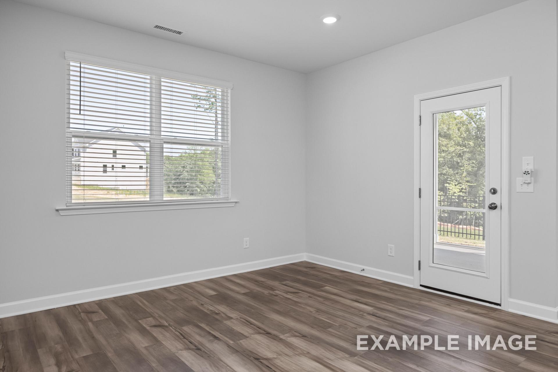 Spacious master bedroom in The Preston B, light gray walls, large windows with blinds, glass patio door, hardwood floors, Davidson Homes Wendell NC