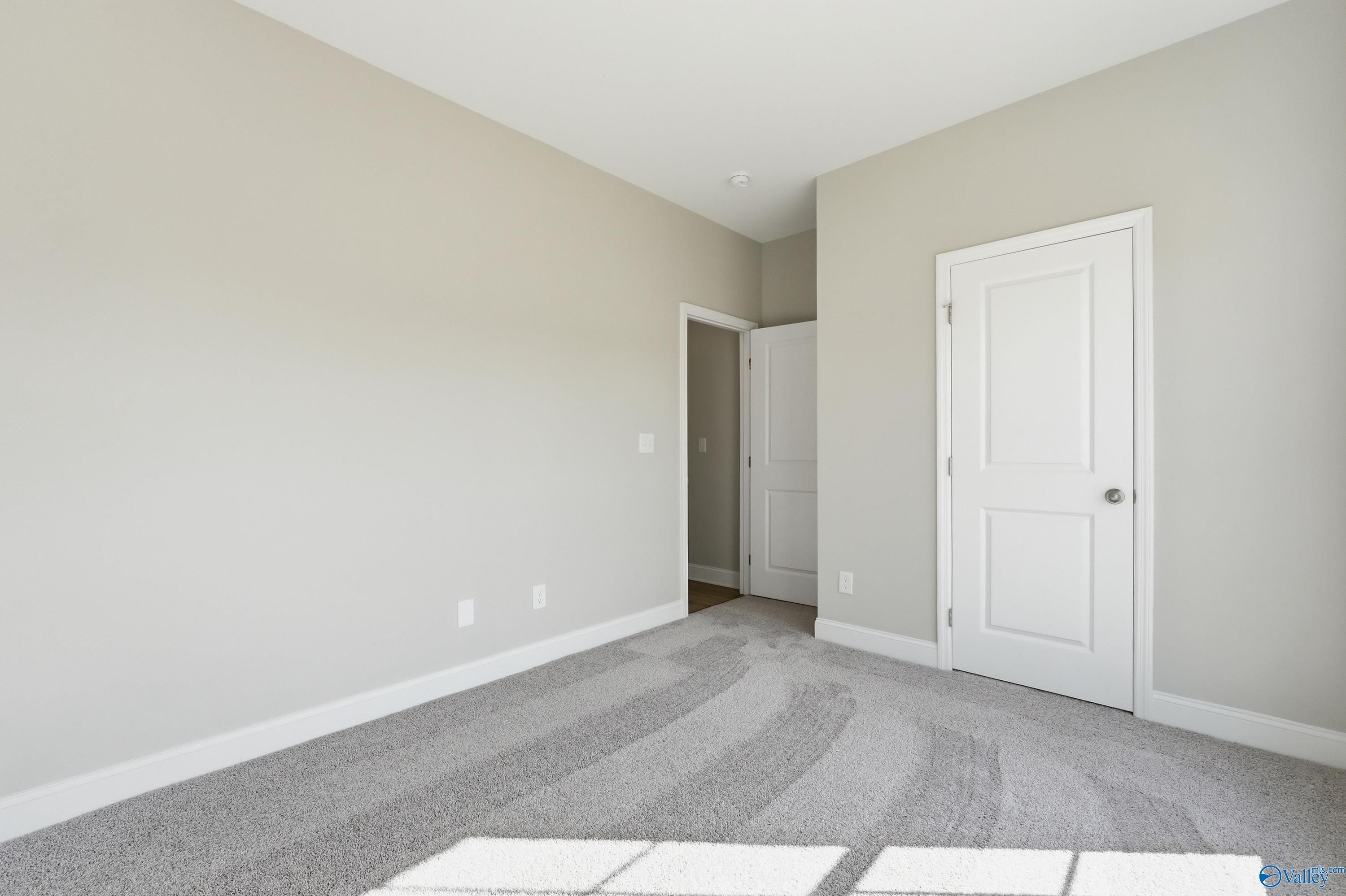 Empty secondary bedroom featuring beige walls, white doors, and light carpet in The Asheville floor plan, Spragins Cove, Huntsville AL