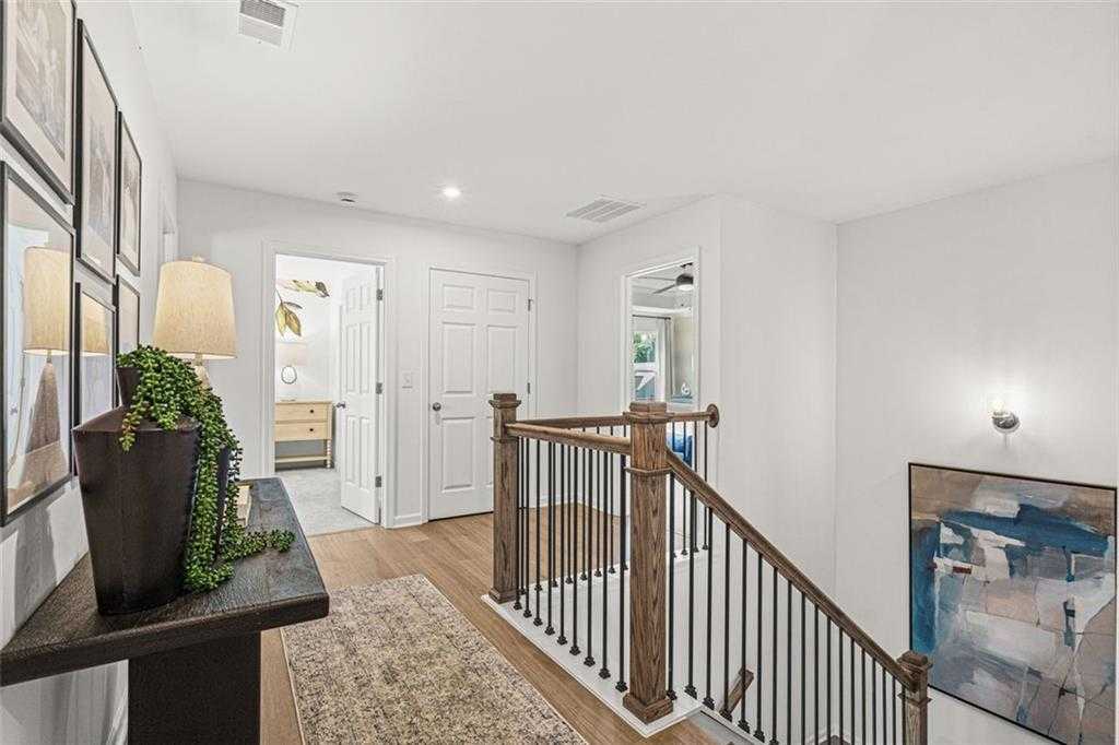 Elegant wooden staircase with metal balusters in bright hallway, console table with plant and lamp, Wehunt Meadows 5-bedroom home, Hoschton, GA