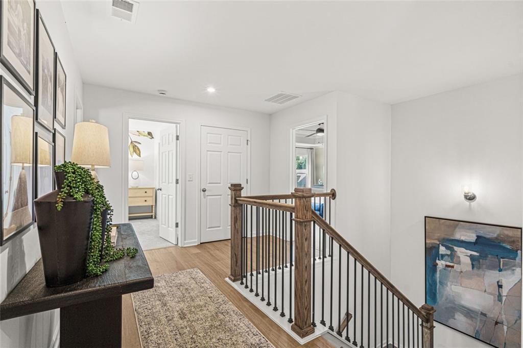 Elegant wooden staircase with metal balusters in bright hallway, console table with plant and lamp, Wehunt Meadows 5-bedroom home, Hoschton, GA