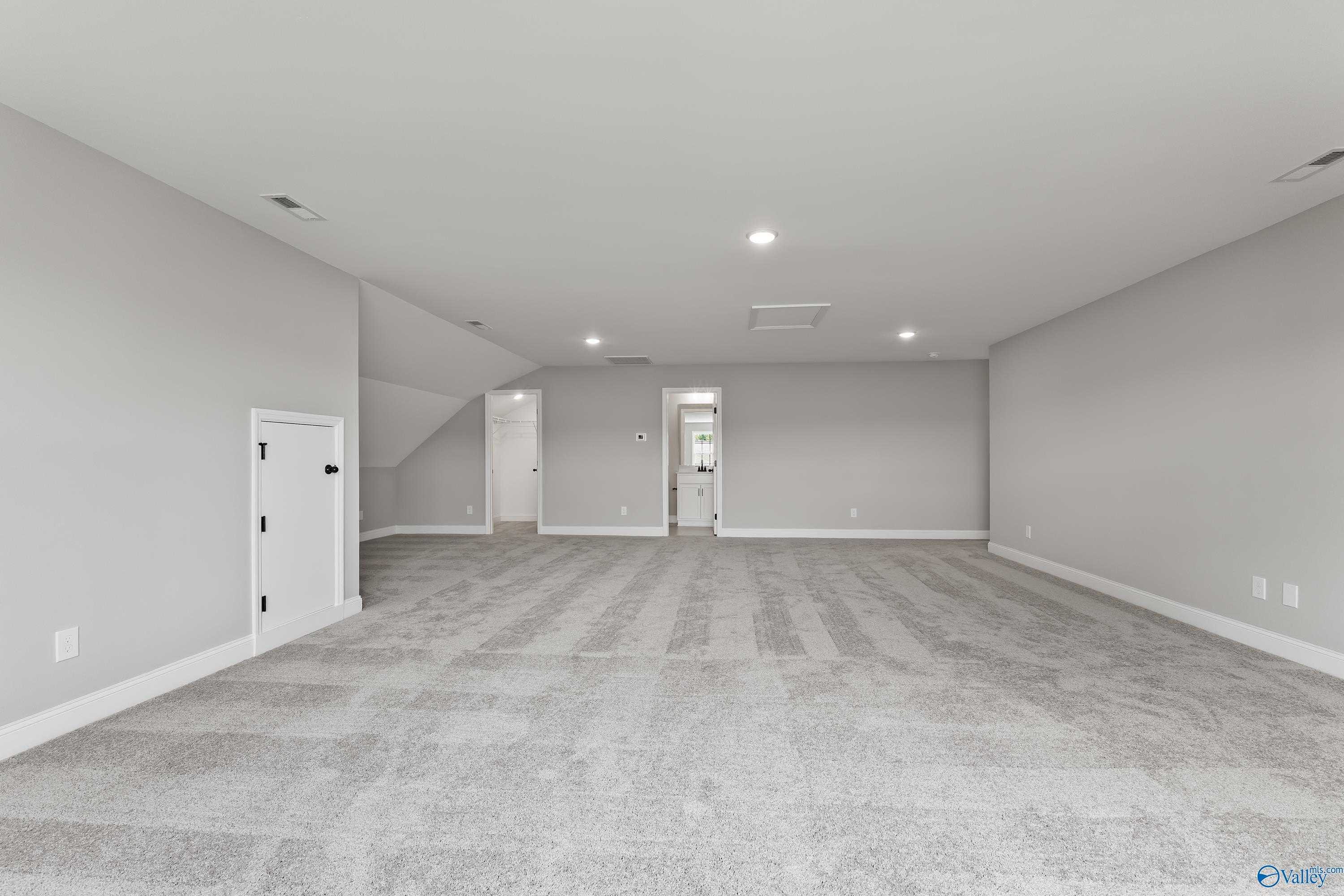 Spacious bonus room with gray carpet, white walls, staircase, and doors in Davidson Homes The Montgomery B With Bonus, Toney, Alabama