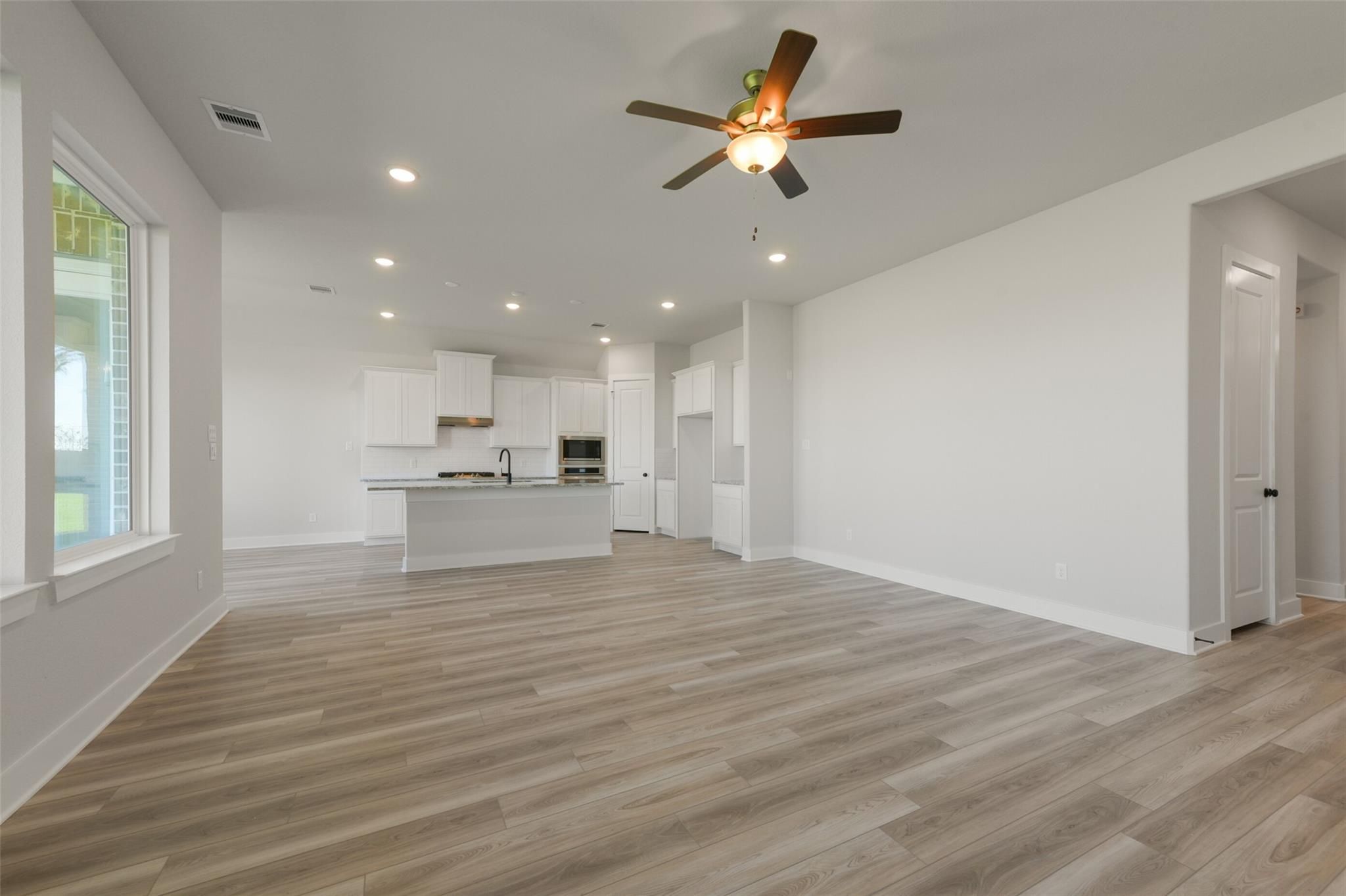 Modern open-concept kitchen with white cabinets, large island, ceiling fan in The Edward C 3-bedroom home, Lago Mar, Texas City