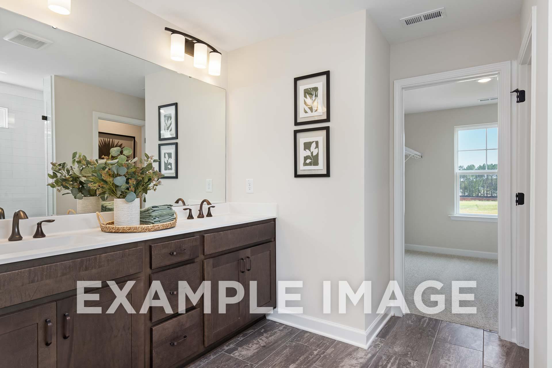 Spacious master bathroom in The Willow E with double dark wood vanity, eucalyptus accents, and walk-in shower