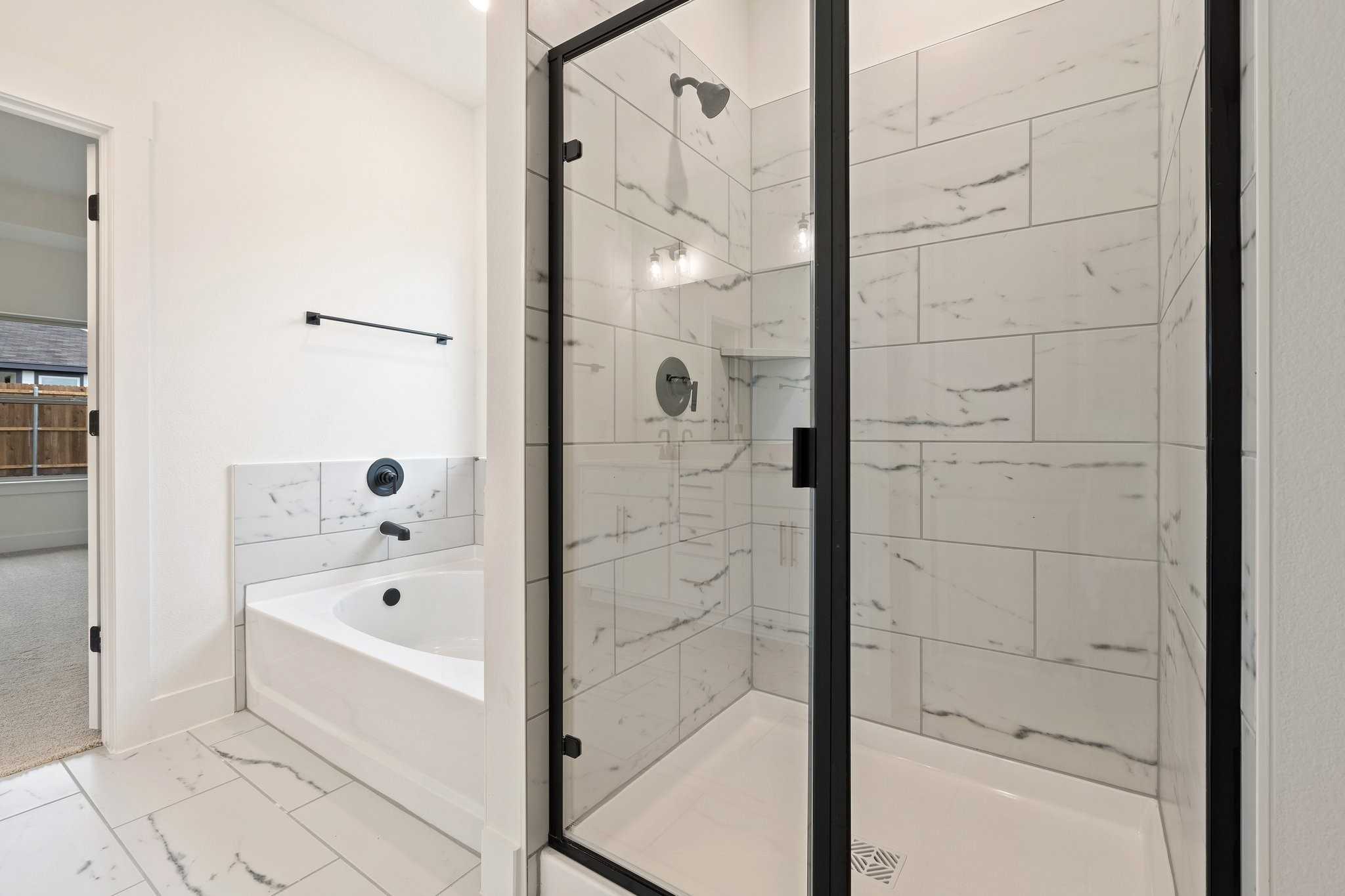 Modern master bathroom featuring freestanding tub, glass-enclosed shower, and white subway tile in Davidson Homes The Rockford C, Josephine, Texas