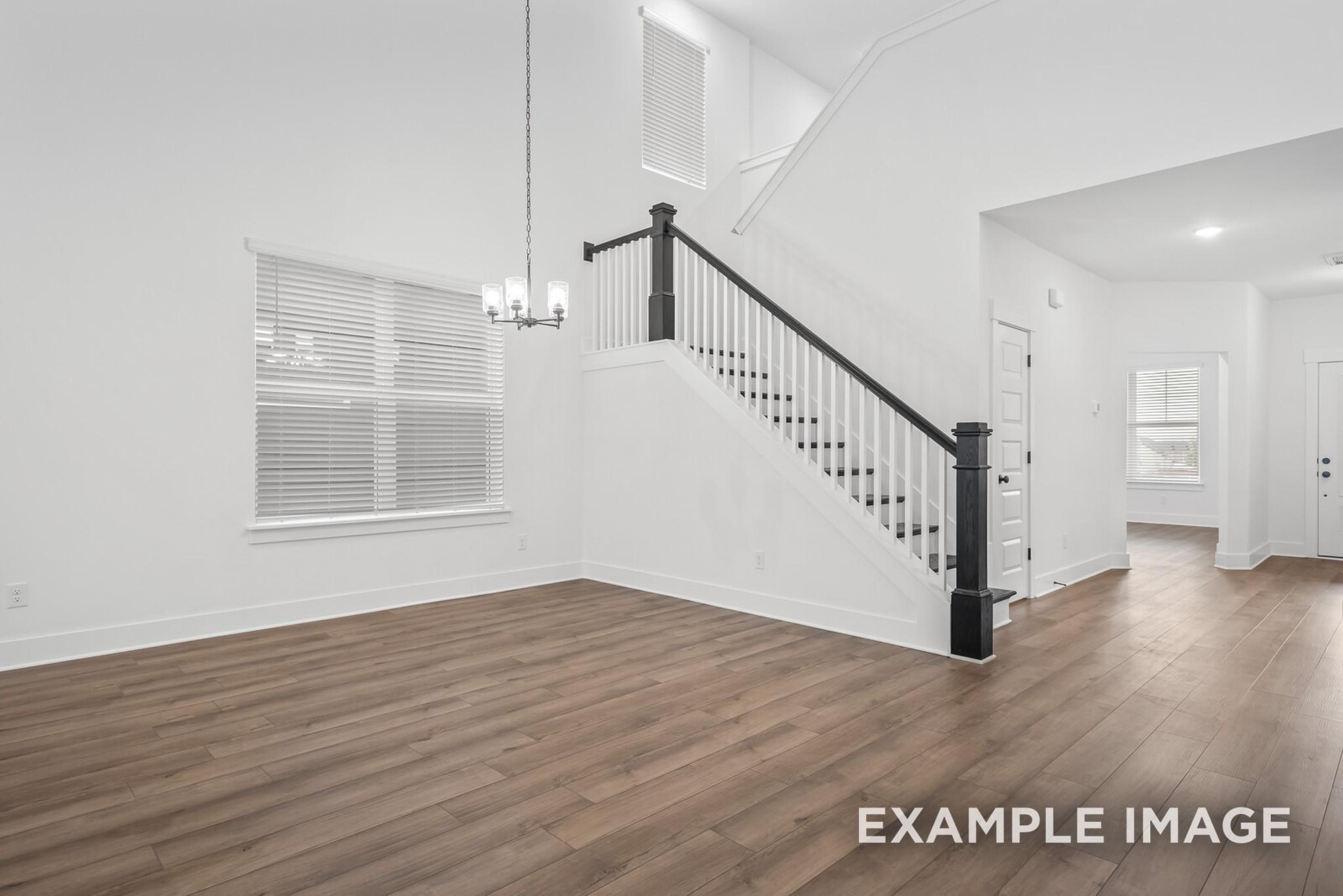 Elegant two-story foyer featuring grand black-railed staircase, hardwood floors, chandelier, and large windows in Davidson Homes The Ridgeport C, Gallatin, Tennessee