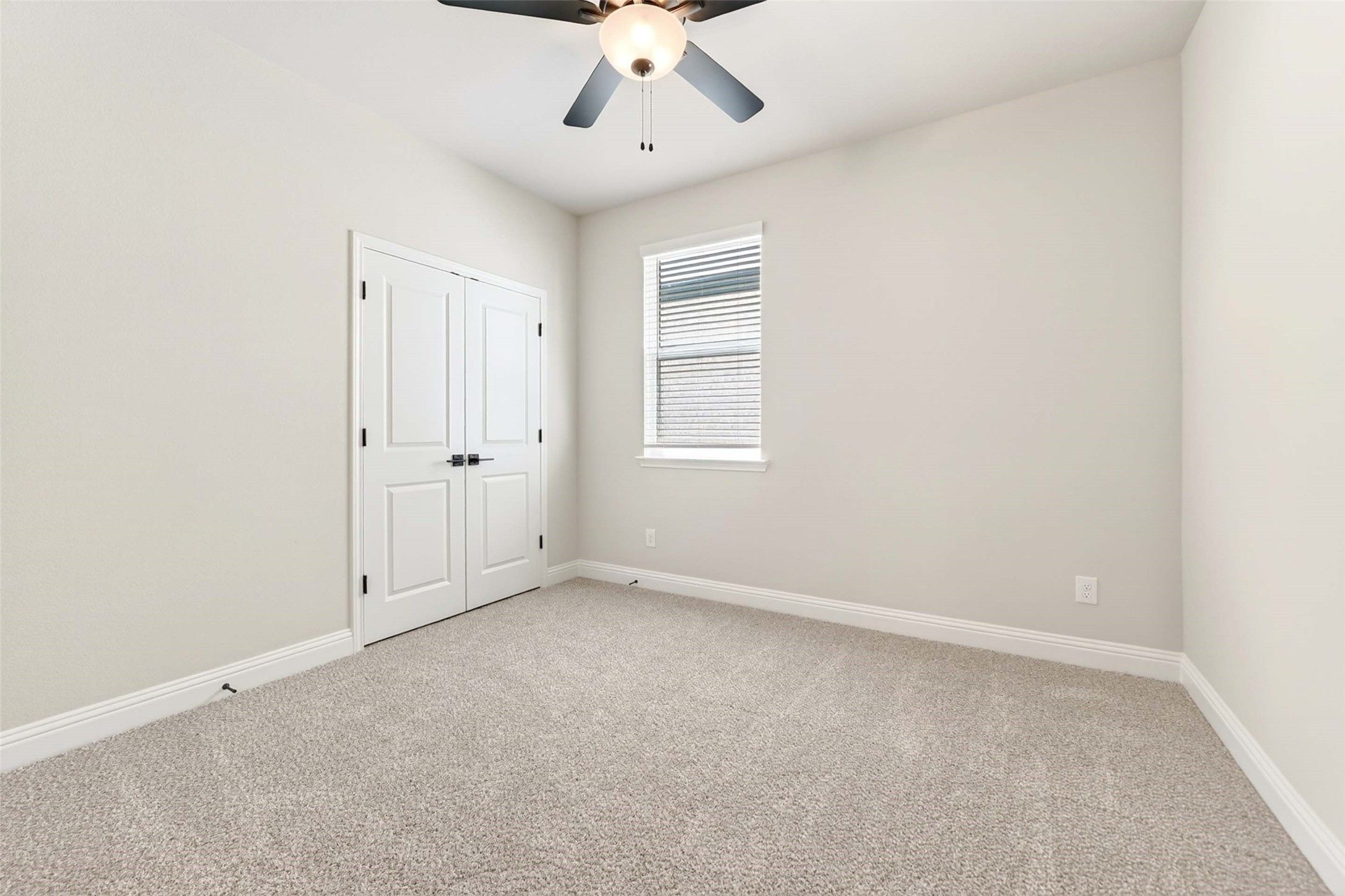 Bright secondary bedroom with plush carpet and ceiling fan in The Holly C floor plan, Parks at Foster Crossing, Anna, TX.