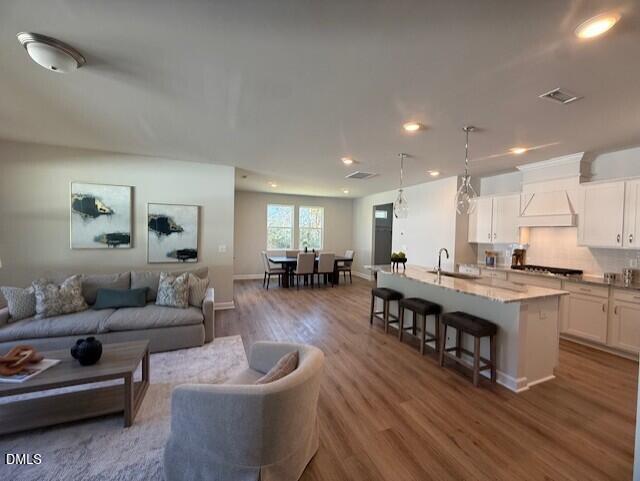 Open-concept kitchen and living room with large white island, dining table, sectional sofa, and hardwood floors in The Preston C, Lillington, NC