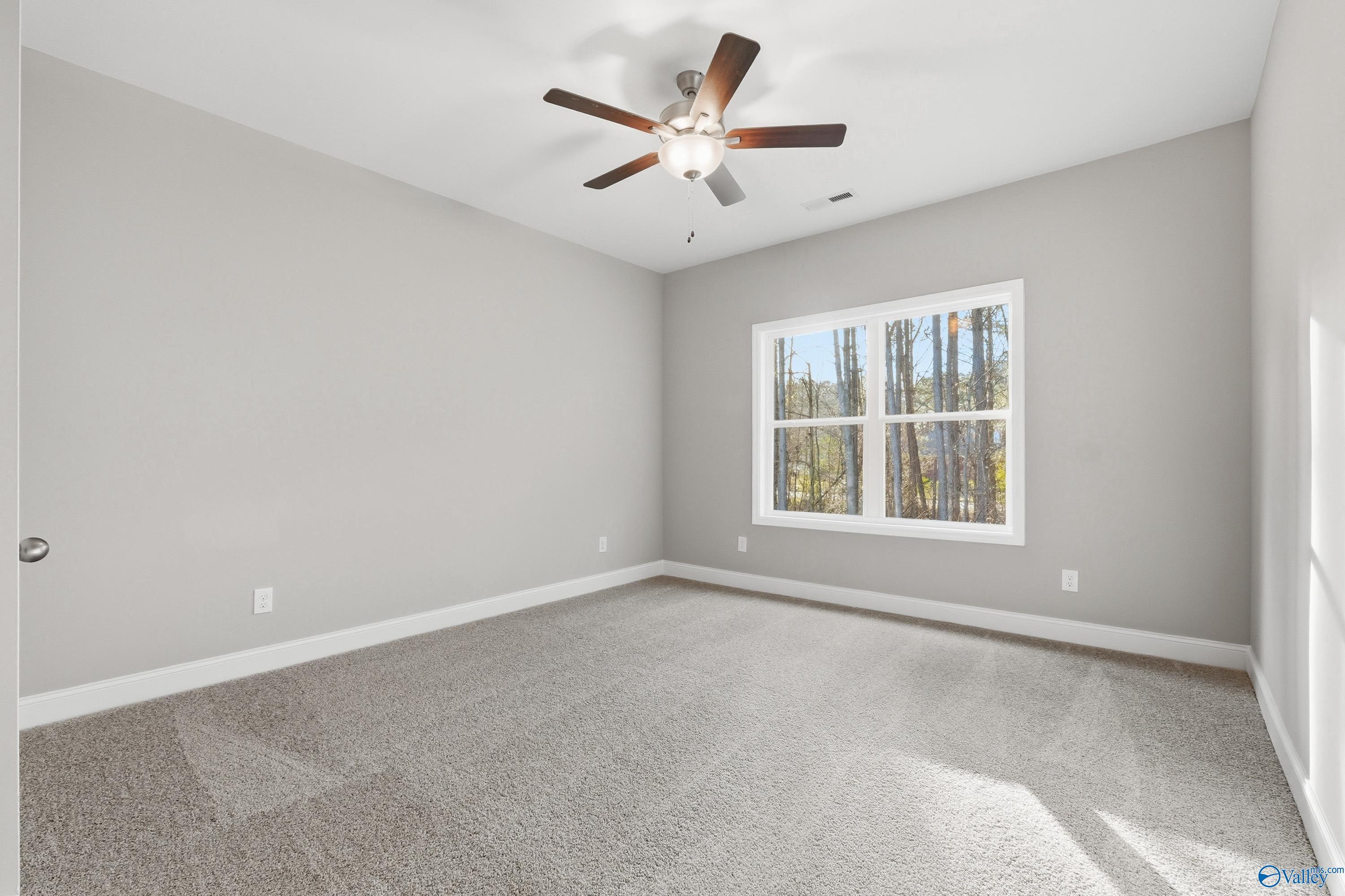 Bright secondary bedroom with ceiling fan, large window to wooded view, gray walls and carpet in Davidson Homes The Asheville, Arab, Alabama