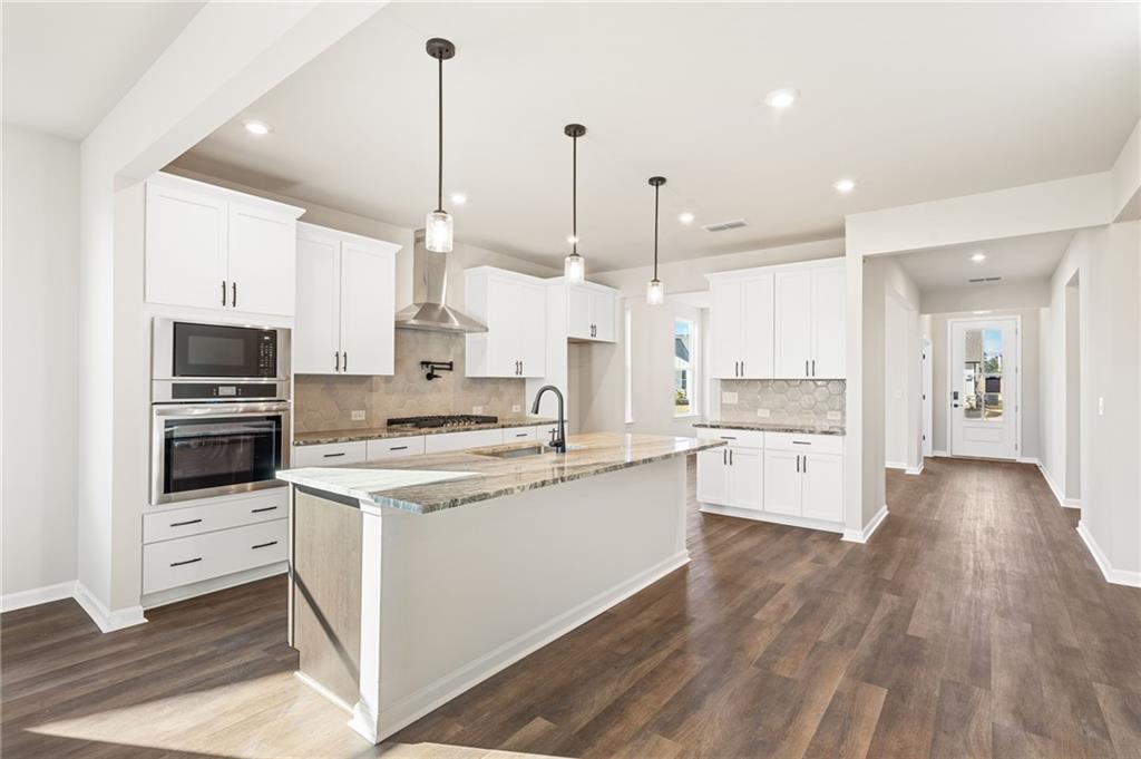 Modern open-concept kitchen with white shaker cabinets, quartz waterfall island, stainless appliances in Davidson Homes The Glenwood A, Loganville GA
