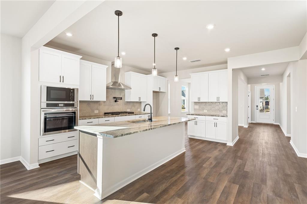 Modern kitchen featuring white shaker cabinets, granite waterfall island, stainless steel appliances in The Glenwood A, Loganville, GA