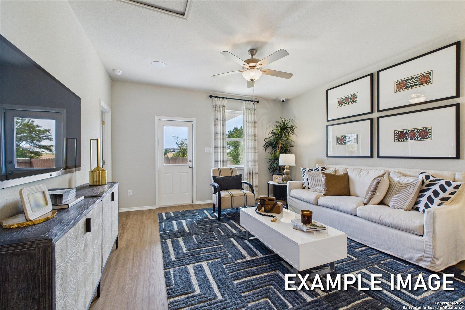 Cozy living room with white sofa, mounted TV, ceiling fan, and sliding doors in Davidson Homes The Sabine C, San Antonio, Texas
