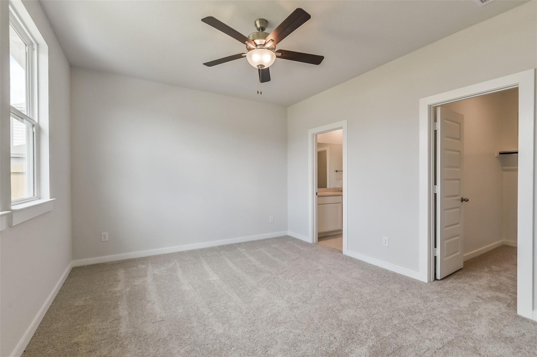 Bright master bedroom with ceiling fan, en-suite bath, and walk-in closet in Davidson Homes The Frio G, Cleveland, Texas