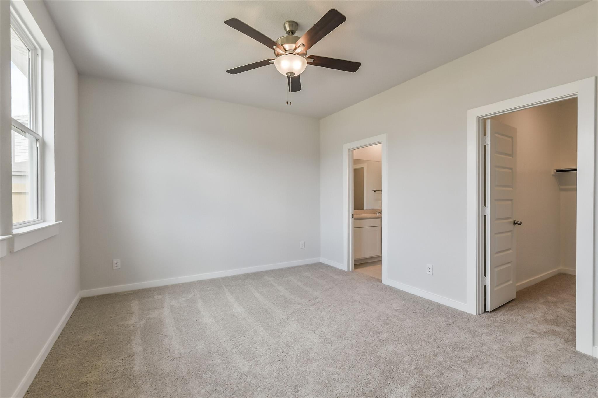 Bright master bedroom with ceiling fan, en-suite bath, and walk-in closet in Davidson Homes The Frio G, Cleveland, Texas