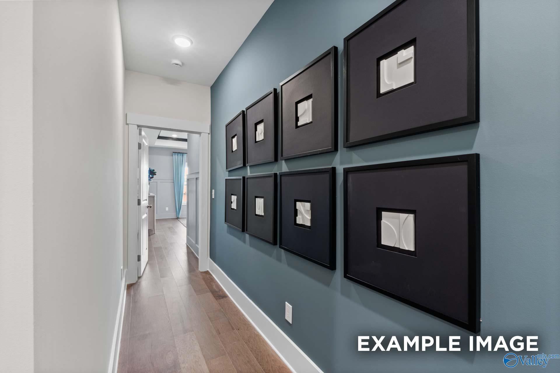Elegant hallway with blue accent wall, black framed art, and hardwood floors in The Finleigh home, Riverton Preserve, Huntsville, Alabama