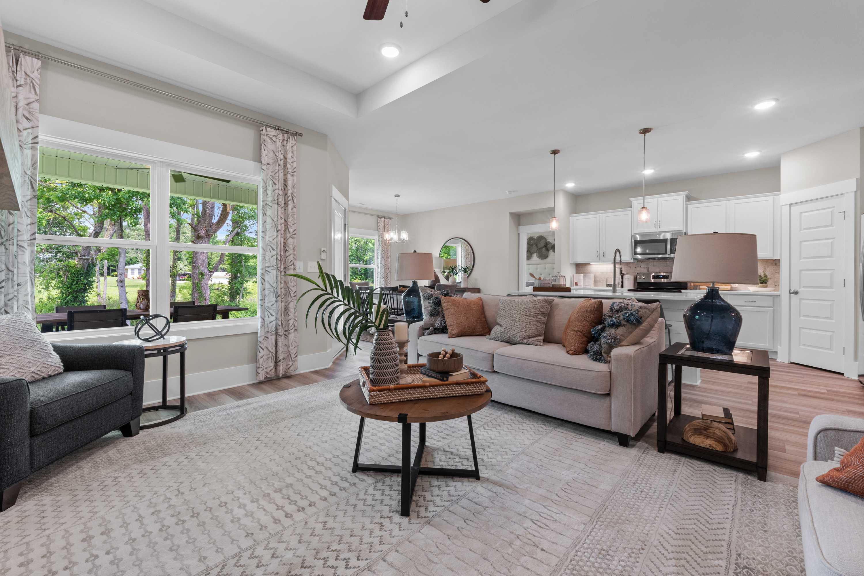 Spacious open-concept living room at The Highlands in Arab Alabama with neutral sofa, modern kitchen, and large windows
