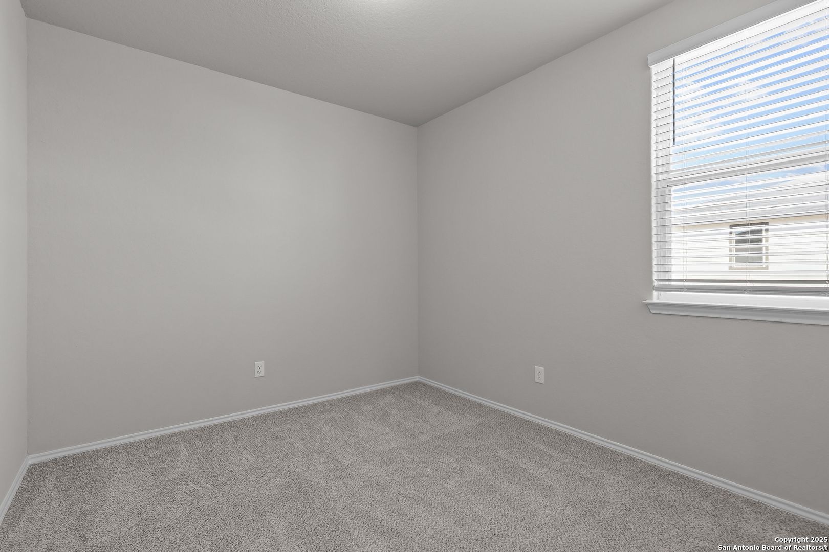 Spacious empty bedroom with gray walls, carpet floor, and large window in Davidson Homes The Colorado B, San Antonio, Texas