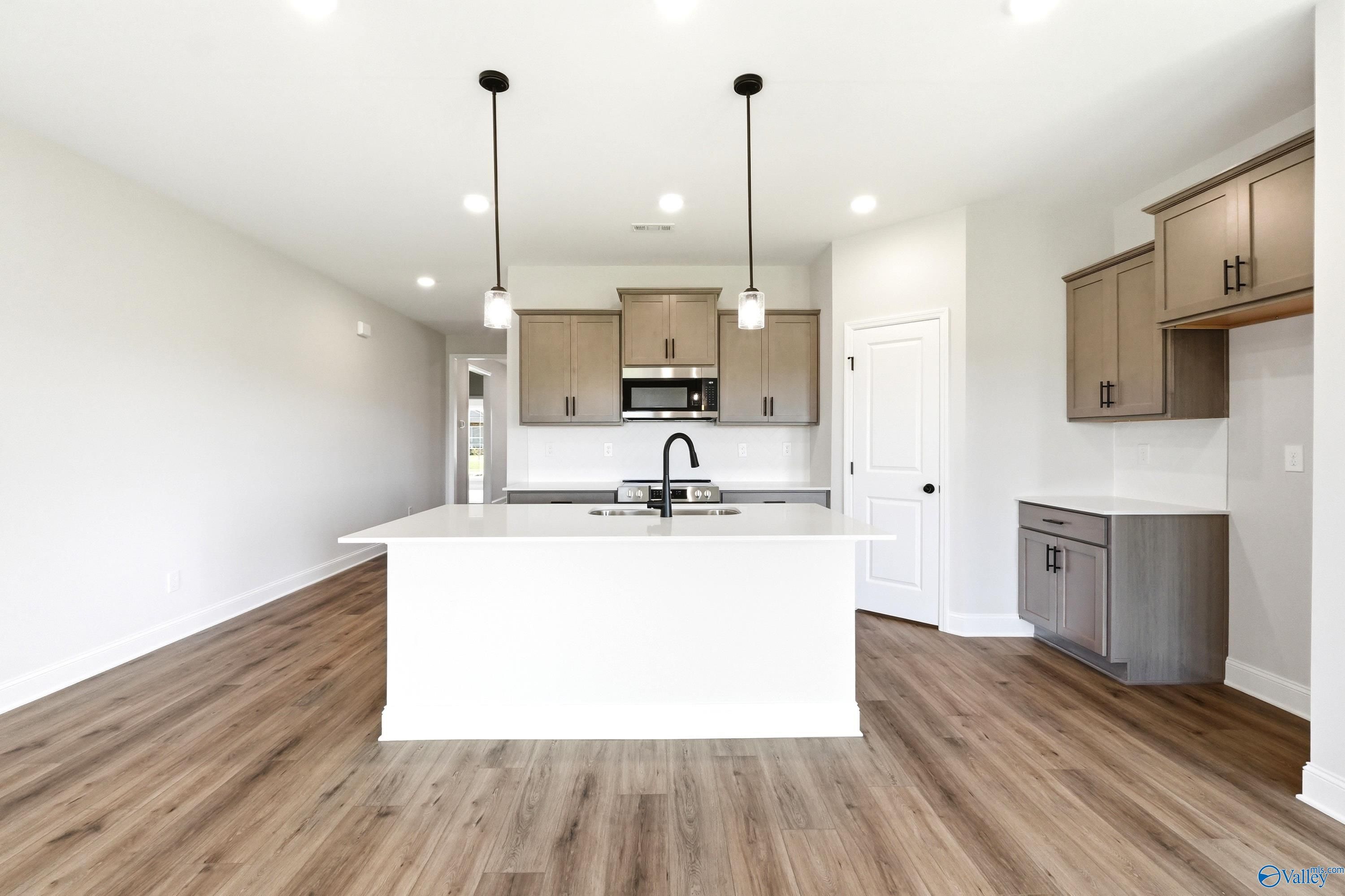 Modern open-concept kitchen with white island and grey cabinets in The Daphne floor plan, Clearview, Hazel Green, Alabama.