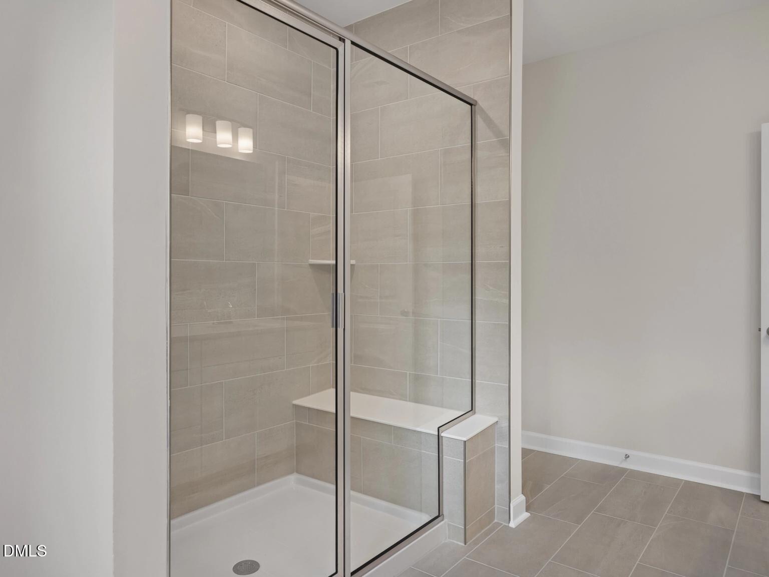 Modern frameless glass shower with tiled walls and built-in bench in master bath, The Beech B by Davidson Homes, Wake Forest, NC