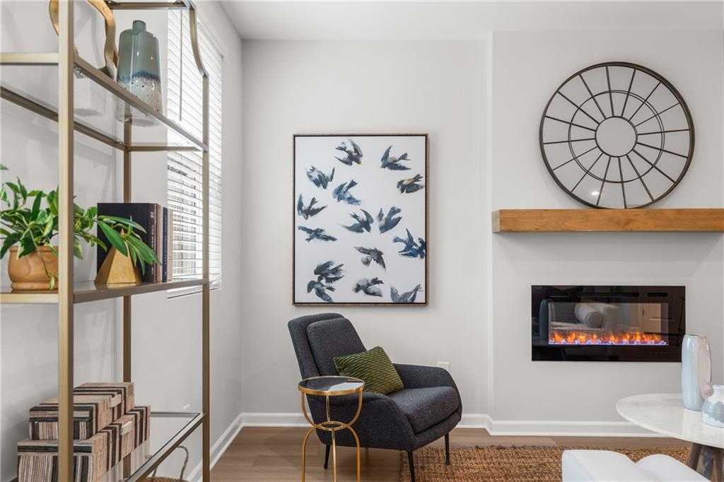 Cozy living room with gas fireplace, gold bookshelves, bird wall art, green armchair in Davidson Homes The Durant A, Emerson, Georgia