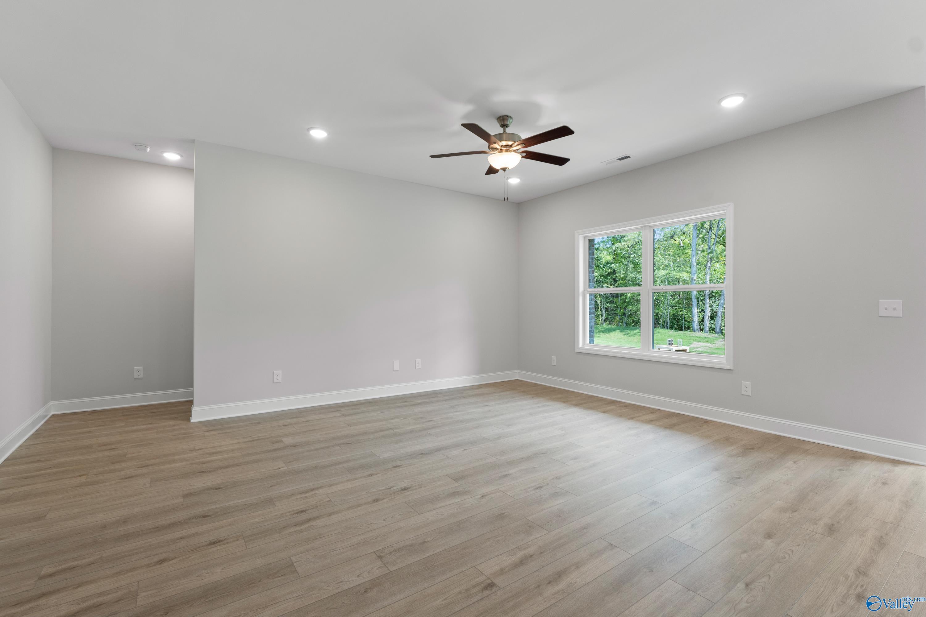 Bright living room with hardwood floors, dual ceiling fans, and large windows in Davidson Homes The Asheville, Huntsville AL