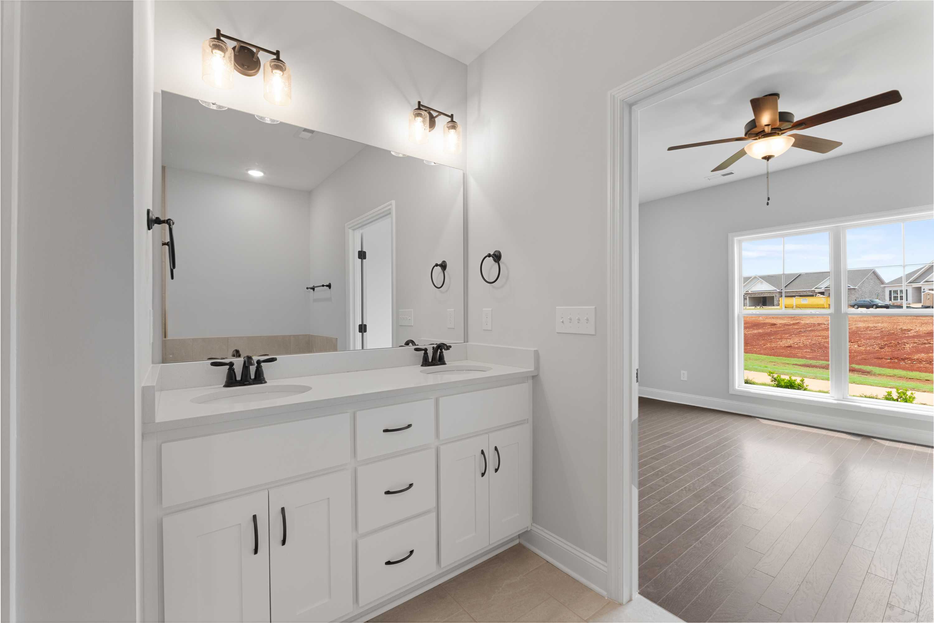 Modern primary bathroom at The Villas at Barnett's Crossing in Madison AL with double vanity, white cabinets, and open doorway