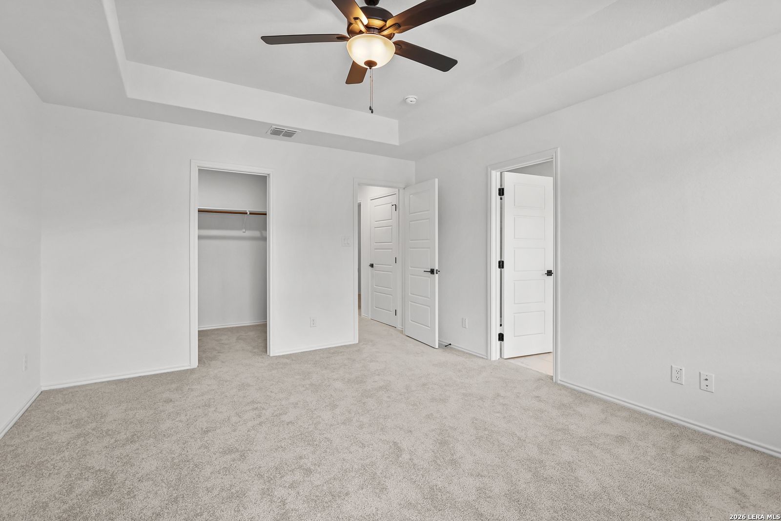 Spacious bedroom with tray ceiling and walk-in closet in The Gillian C floor plan at Meadows at Oak Creek, San Antonio.