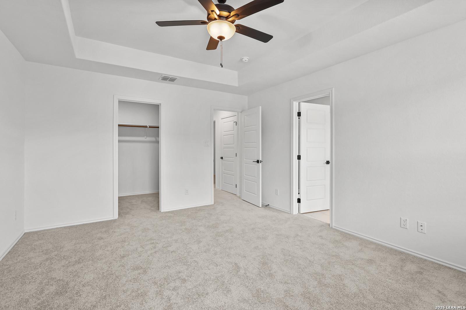 Spacious bedroom with tray ceiling and walk-in closet in The Gillian C floor plan at Meadows at Oak Creek, San Antonio.