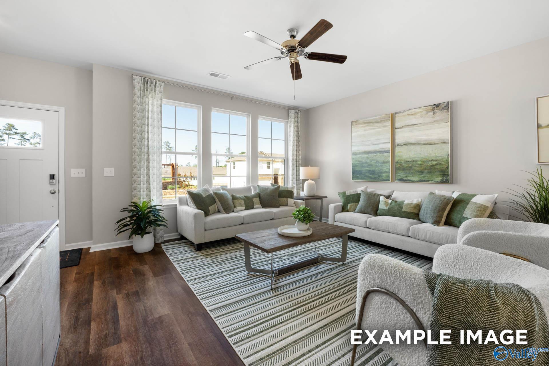 Inviting living room with beige sofas, ceiling fans, large windows, and potted plants in Davidson Homes The Stella, Madison, Alabama