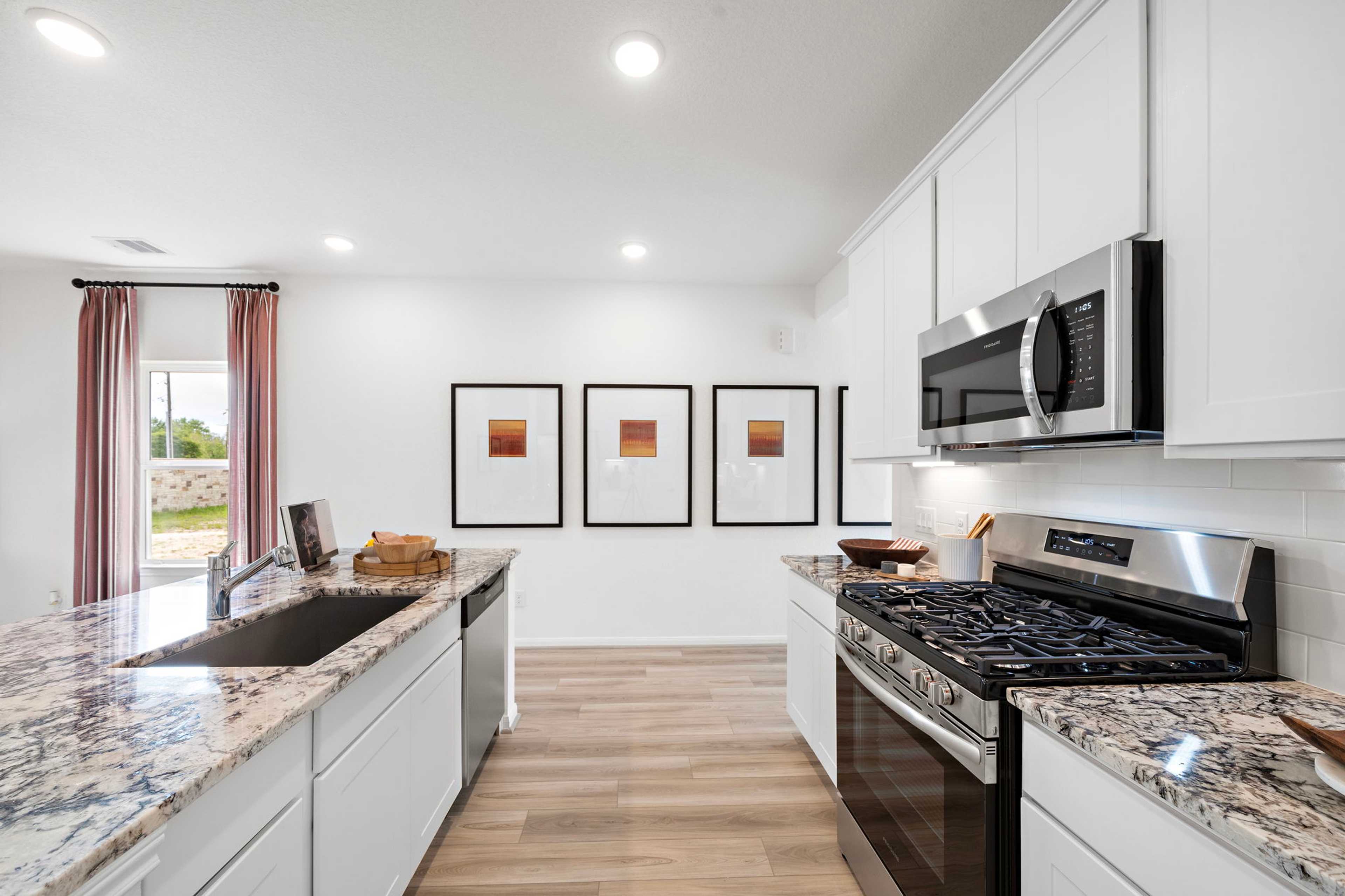 Spacious modern kitchen at The Villages at WestPointe in Dayton Texas with white cabinets, granite island, stainless appliances, hardwood floors