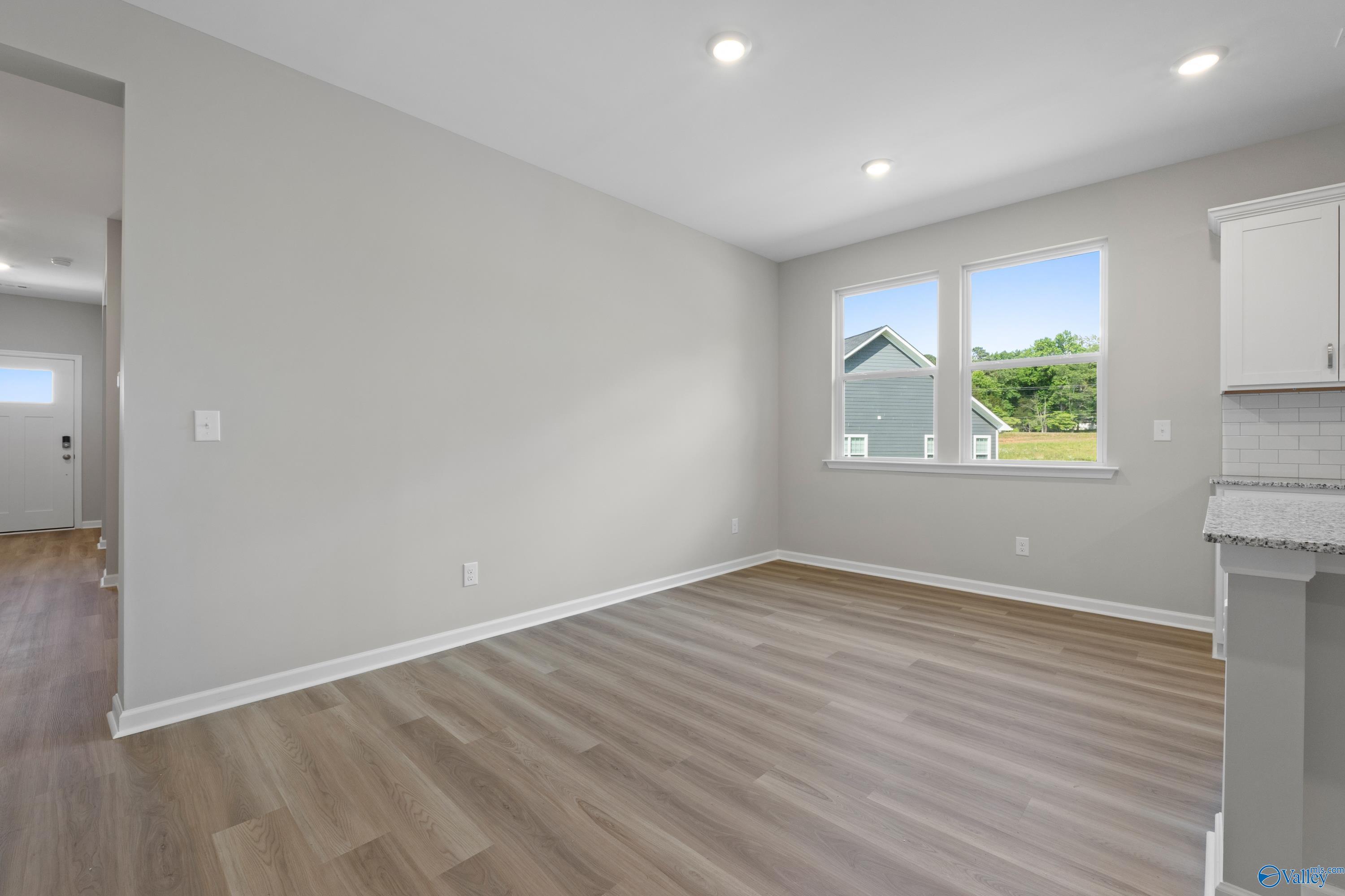 Open-concept living room with hardwood floors, large windows, and gray walls in The Polaris 3-bedroom home, Fayetteville, TN