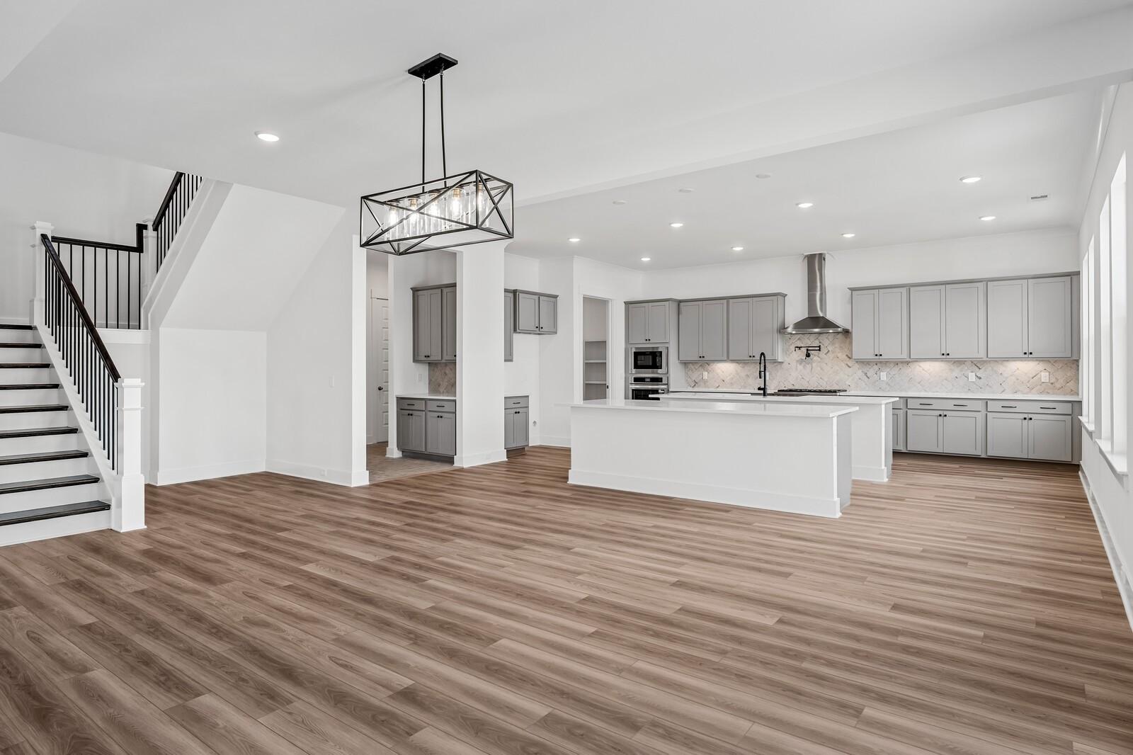 Open-concept kitchen and family room with white shaker cabinets, large island, stainless appliances, and hardwood floors in The Alston A, Murfreesboro, TN