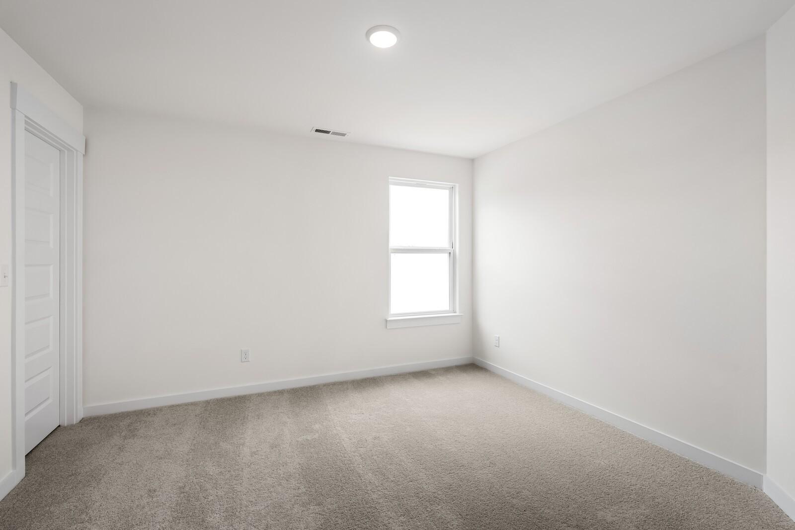 Bright secondary bedroom with white walls, beige carpet, large window in The Ridgeport 4-bedroom home, Gallatin, Tennessee