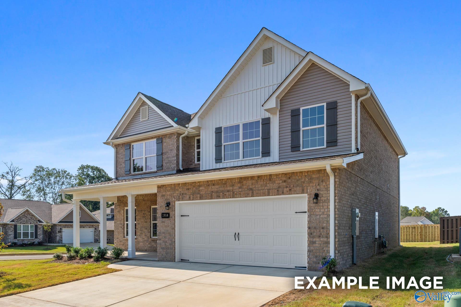 Two-story brick and siding home with two-car garage, covered porch, and lush landscaping in Creek Grove, New Market, Alabama