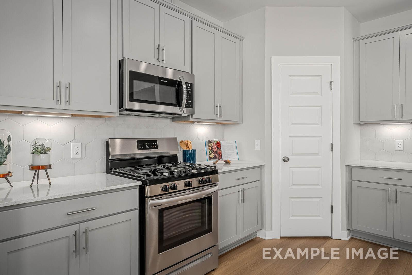 Spacious kitchen in The Franklin B featuring white shaker cabinets, stainless steel gas range, oven, subway tile backsplash