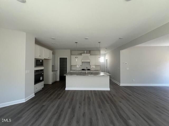 Modern open-concept kitchen featuring white shaker cabinets, granite island with sink, stainless appliances in The Adalynn A floor plan, Lillington, NC