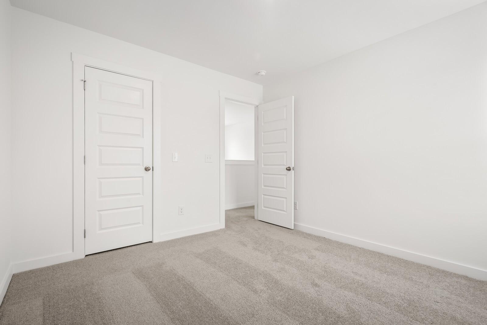 Bright master bedroom with open closet and bathroom doors on beige carpet in Davidson Homes The Gordon C, White House, TN