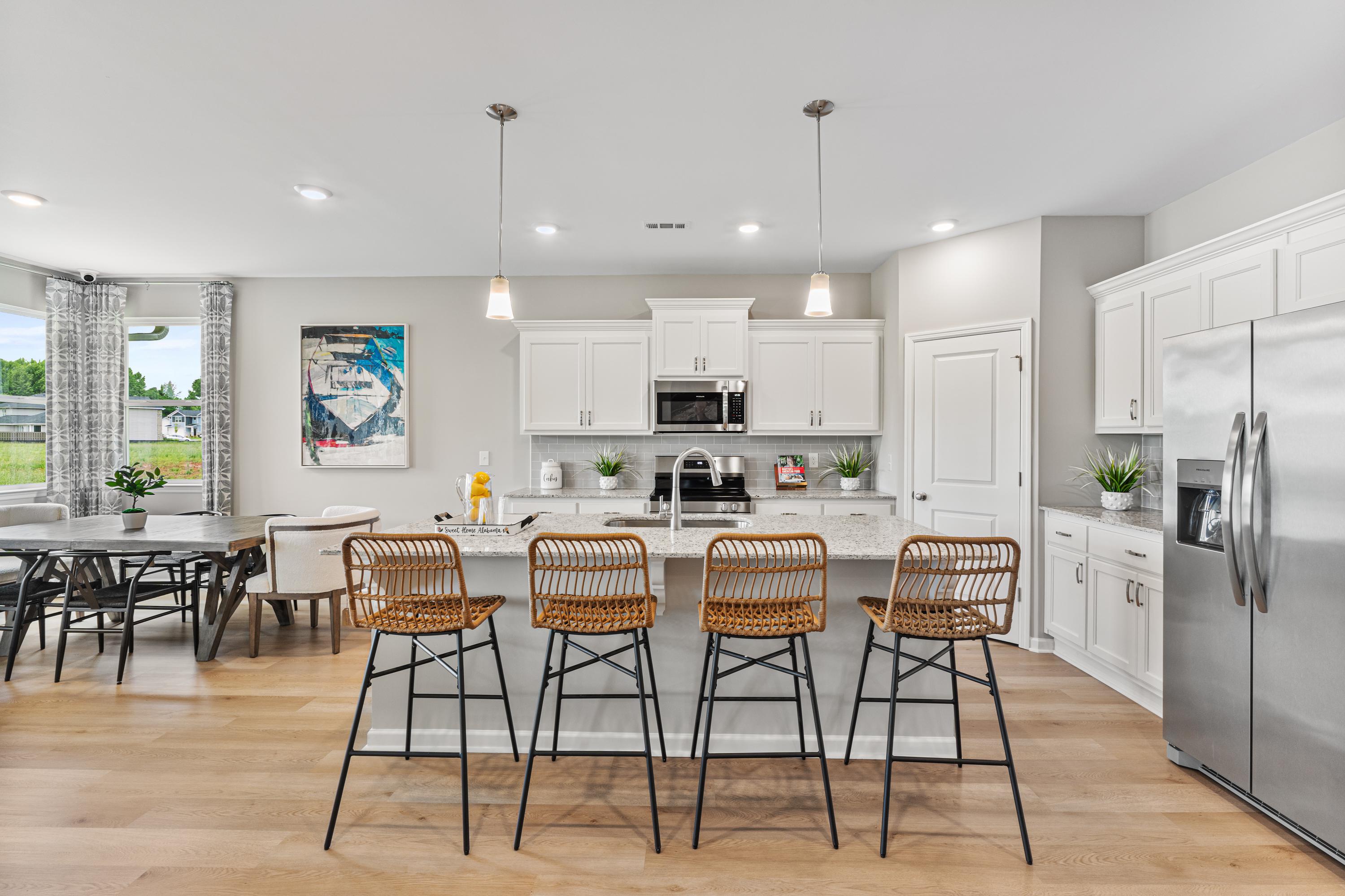 Spacious open-concept kitchen at Forest Glen in Hazel Green, Alabama with white cabinets, island bar stools, and hardwood floors