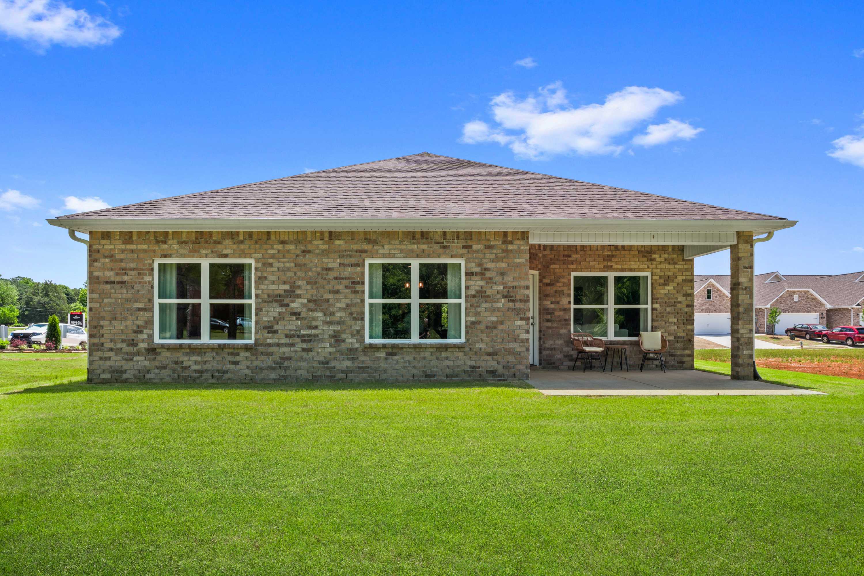 Brick ranch-style home exterior at Hollon Meadow in Decatur, Alabama with covered side porch, seating, and lush green lawn