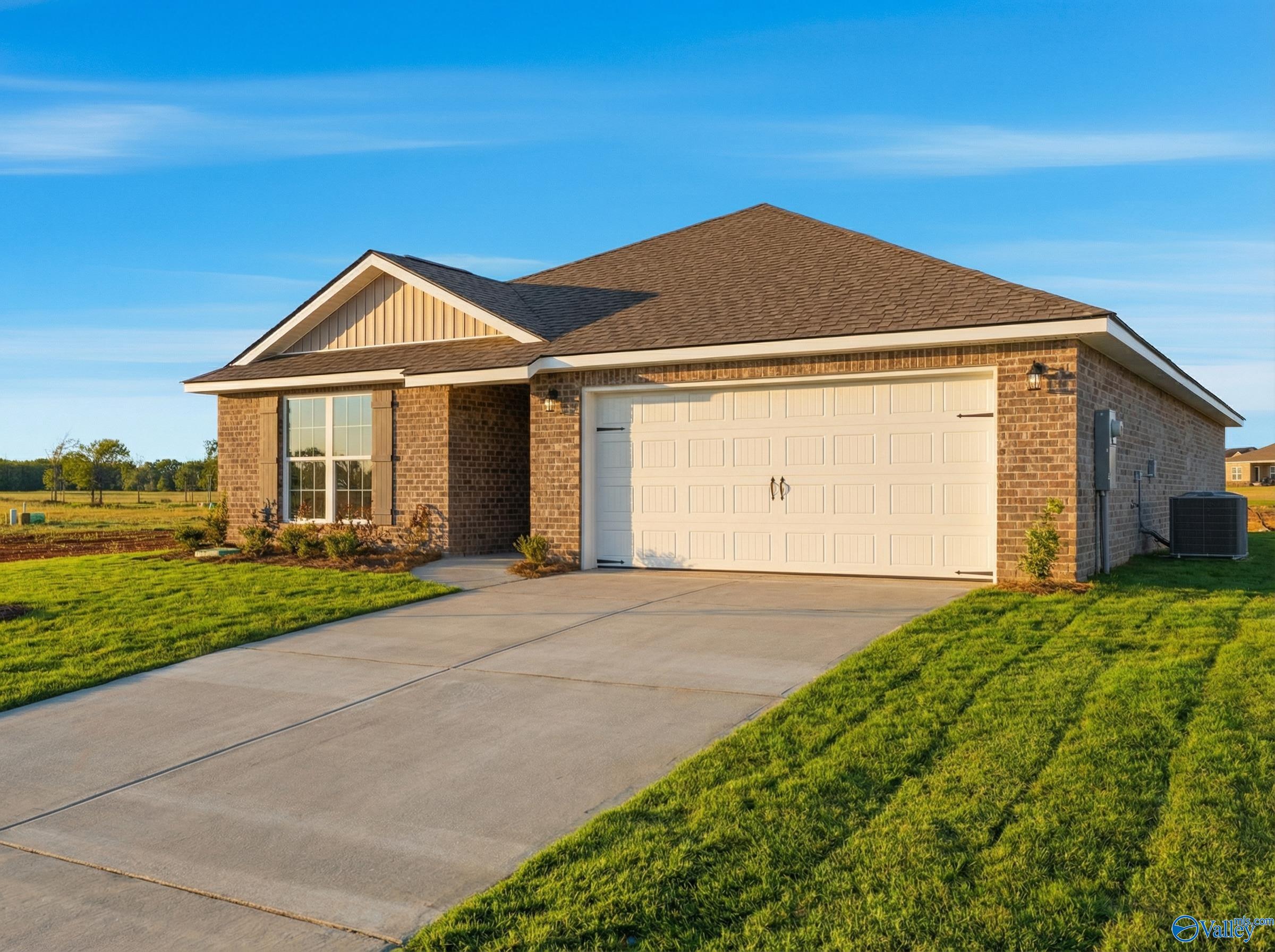 Modern 1-story brick home with gabled roof, 2-car garage, concrete driveway, and lush green lawn in Heritage Lakes, New Market, Alabama - Davidson Homes The Franklin